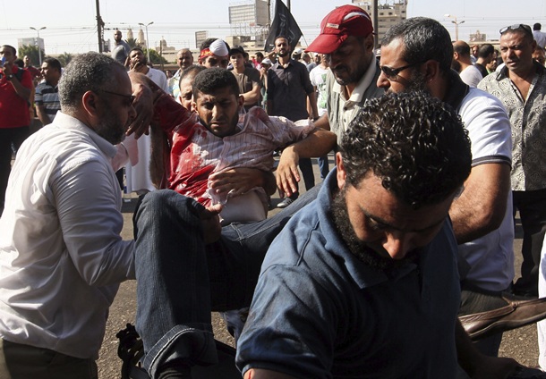 Varios hombres trasladan a un herido durante choques entre simpatizantes de los Hermanos Musulmanes del depuesto presidente egipcio Mohamed Mursi y la policía. | EFE