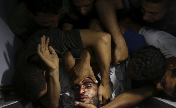 People mourn around the body of a Palestinian militant at a hospital morgue in the central Gaza Strip