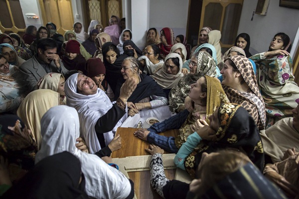 Un grupo de madres llora la muerte de sus hijos, ante los féretros de las víctimas de la matanza. / REUTERS