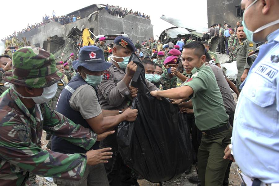 Security forces and rescue teams remove the bodies of victims from the wreckage of an Indonesian military C-130 Hercules transport plane after it crashed into a residential area in the North Sumatra city of Medan, Indonesia,