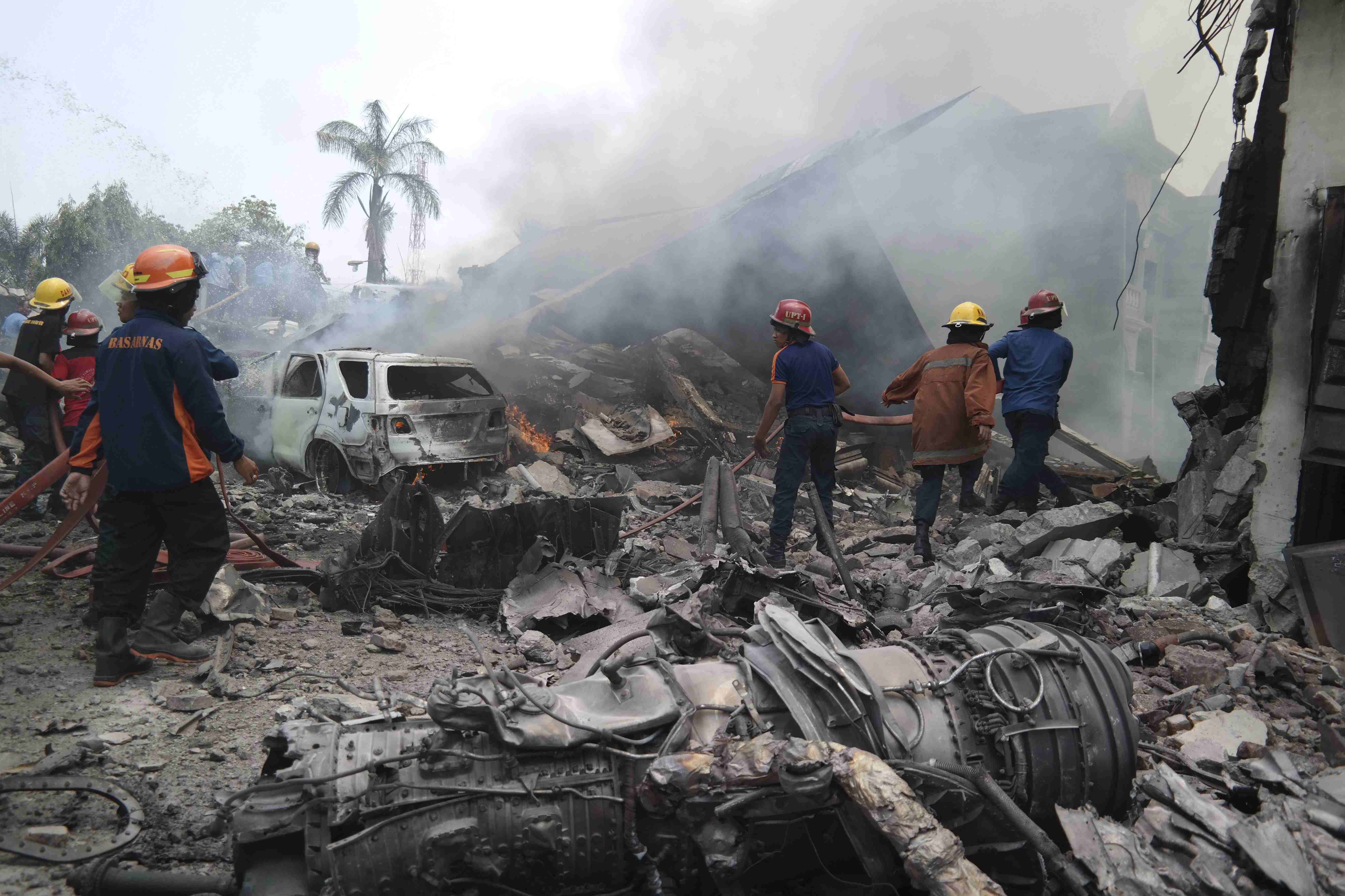 Firemen attempt to extinguish the fire surrounding the wreckage of an Indonesian military transport plane after it crashed in the North Sumatra city of Medan