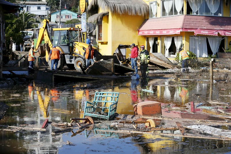 People work on removing the debris of houses and shops destroyed by waves after an earthquake hit areas of central Chile, in Concon city