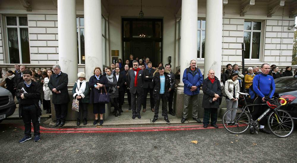 People pause to observe a minute's silence in memory of the victims of the Paris shootings, at the French Embassy in London