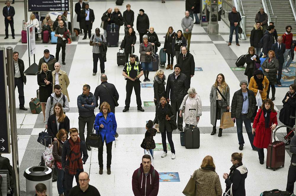 People pause to observe a minute's silence in memory of the victims of the Paris shootings, at Liverpool Street Station in London