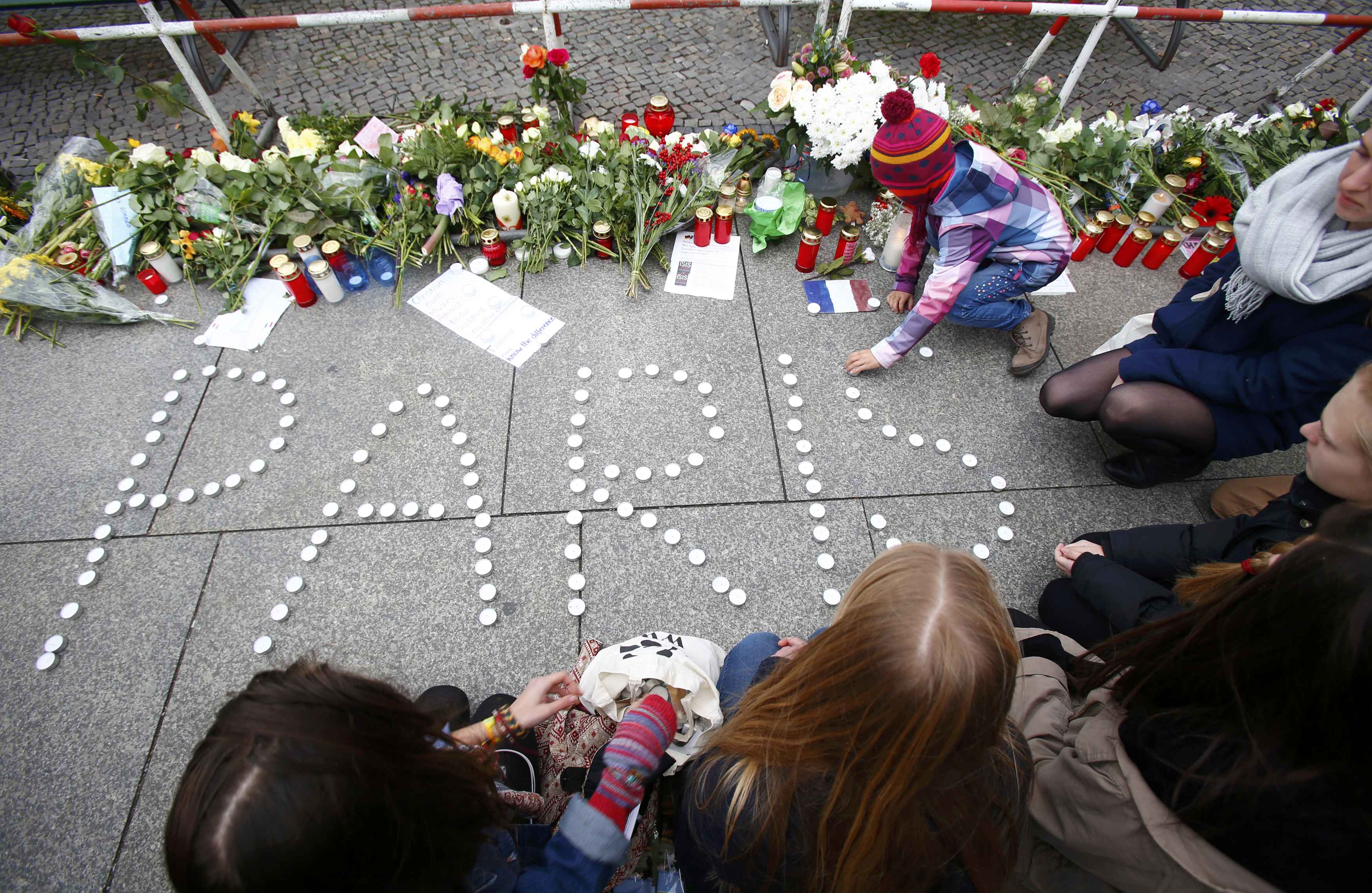 People place candles to form the word “Paris” outside the French embassy in Berlin