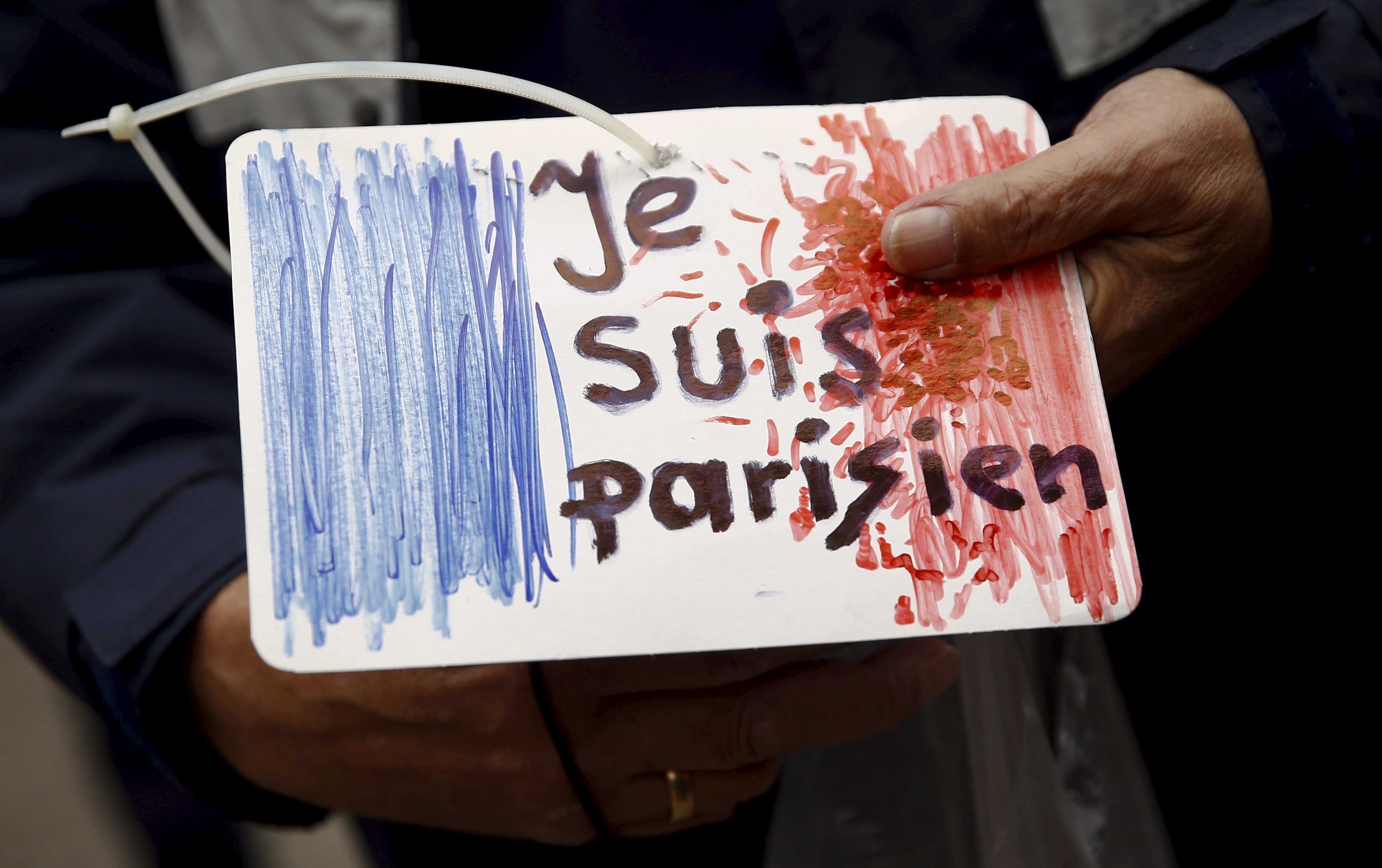 Man holds a drawing in front of the French embassy after attacks in Paris on Friday, in Warsaw