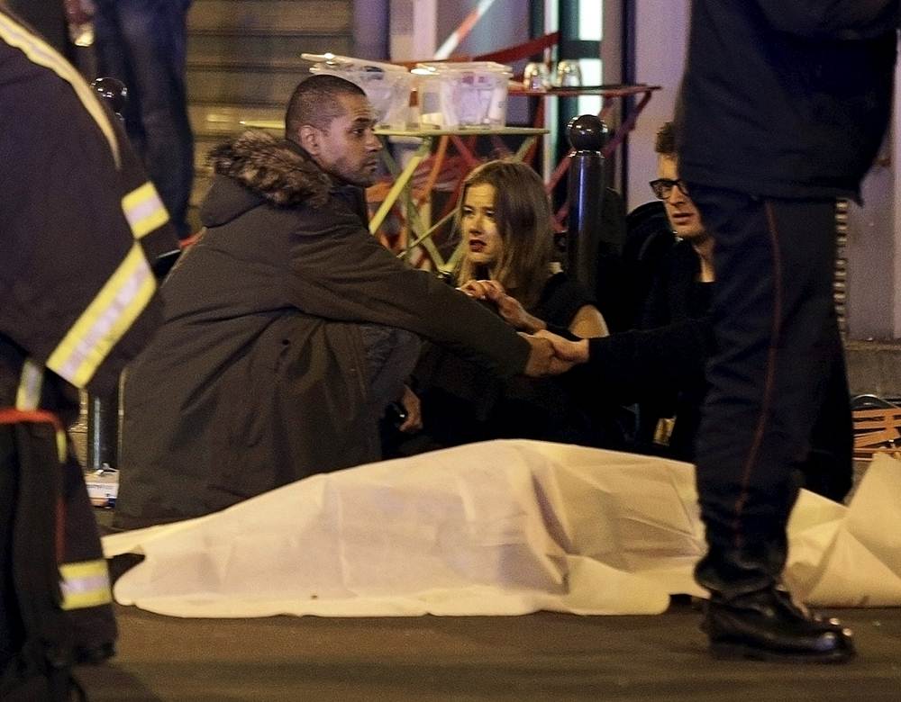 General view of the scene that shows rescue services personnel working near the covered bodies outside a restaurant following a shooting incident in Paris