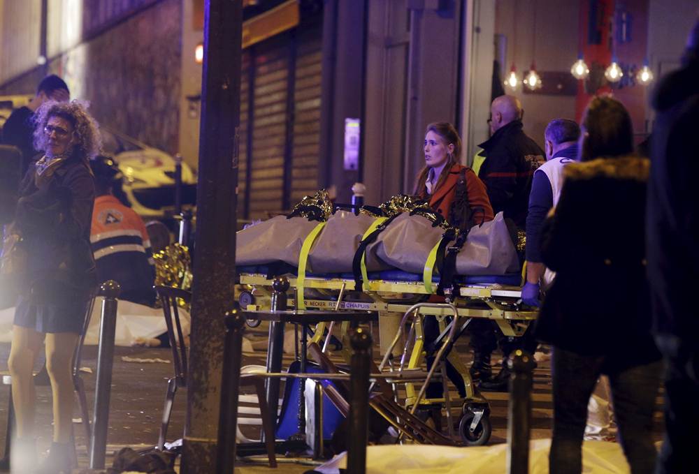 General view of the scene with rescue service personnel who work near the a covered body outside a restaurant following shooting incidents in Paris