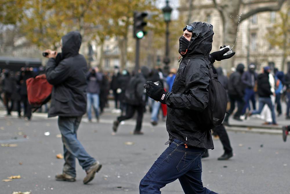 A demonstrator throws a projectile at French CRS police during clashes after the cancellation of a planned climate march following shootings in the French capital, ahead of the World Climate Change Conference 2015 (COP21), in Paris