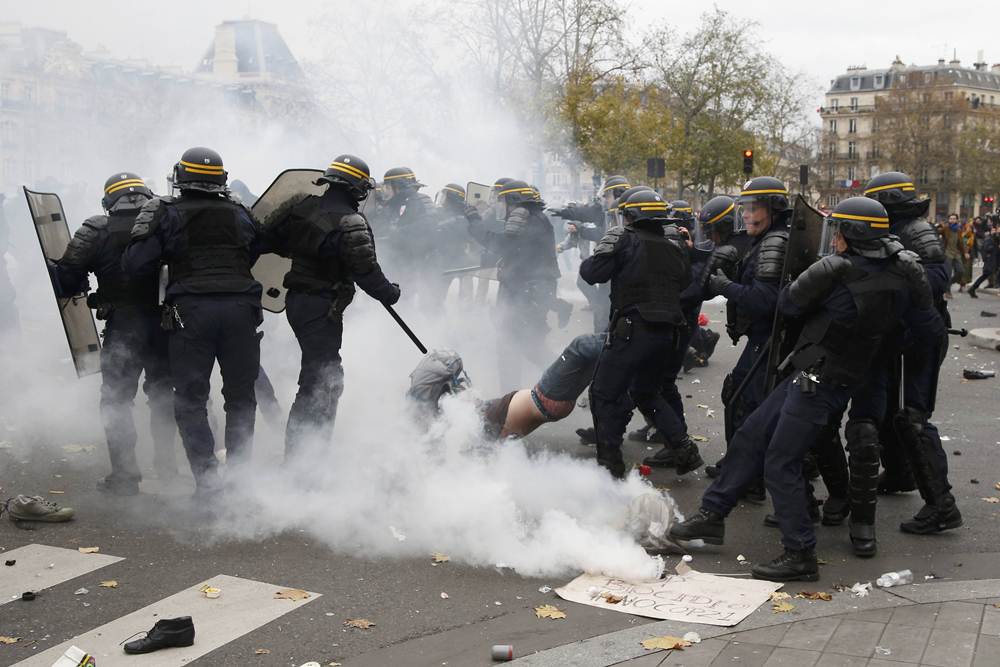 French CRS riot police apprehend a demonstrator during clashes near the Place de la Republique after the cancellation of a planned climate march  ahead of the World Climate Change Conference 2015 in Paris