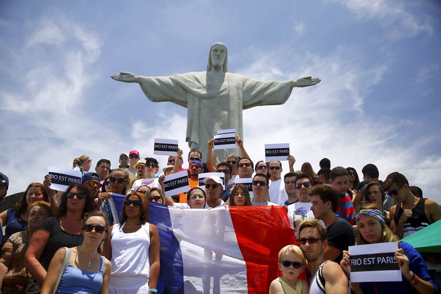 People hold placards and a French flag in front of the Christ the Redeemer statue, in tribute to the victims of Paris attacks, in Rio de Janeiro