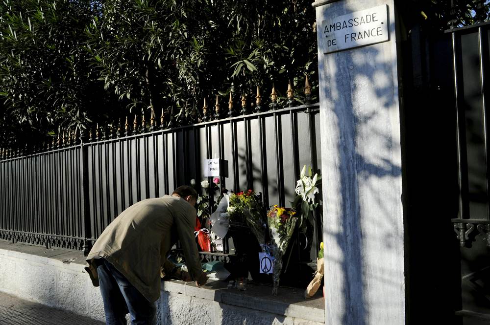 A man lights a candle next to flowers placed in memory of victims of the deadly attacks in Paris, outside the French embassy in Athens