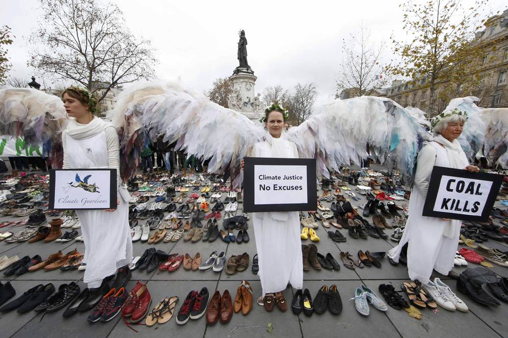 Environmental activists stand among pairs of shoes symbolically placed on the Place de la Republique ahead of the World Climate Change Conference 2015 in Paris