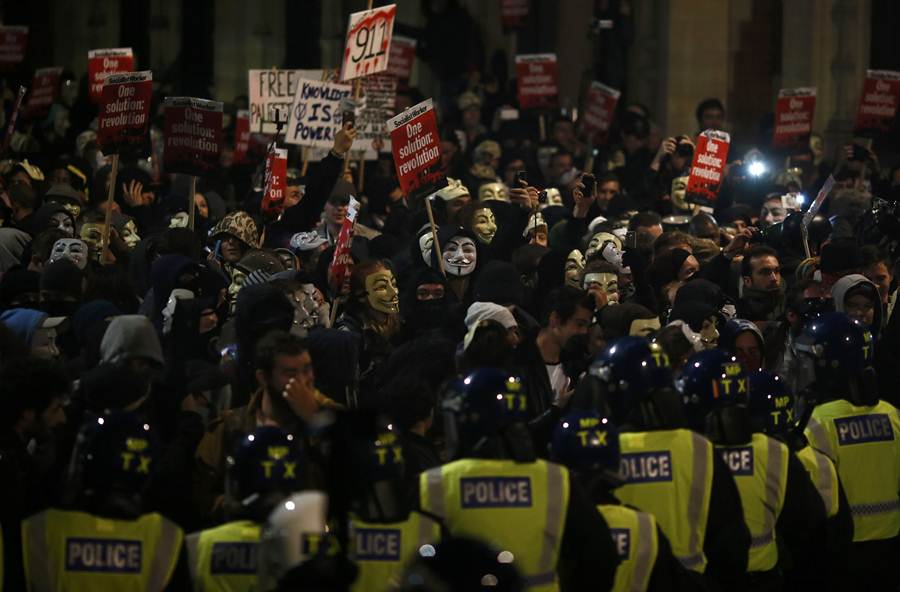 Supporters of the activist group Anonymous face police lines during a protest in London