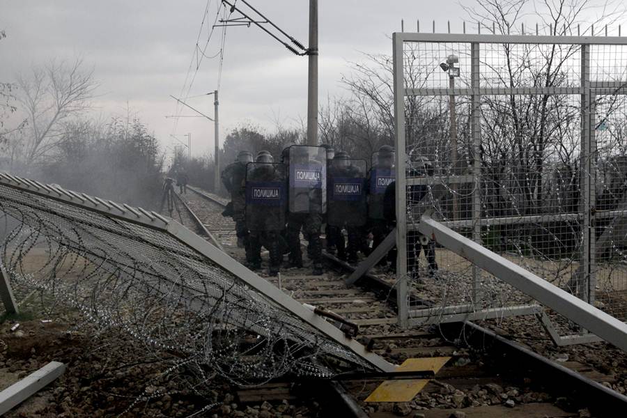 Macedonian riot police officers stand next to part of the border fence brought down by protesting stranded refugees and migrants during a protest at the Greek-Macedonian border, near the Greek village of Idomeni