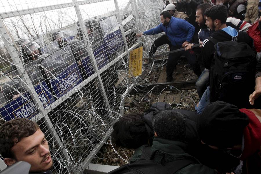 Stranded refugees and migrants try to bring down part of the border fence during a protest at the Greek-Macedonian border, near the Greek village of Idomeni
