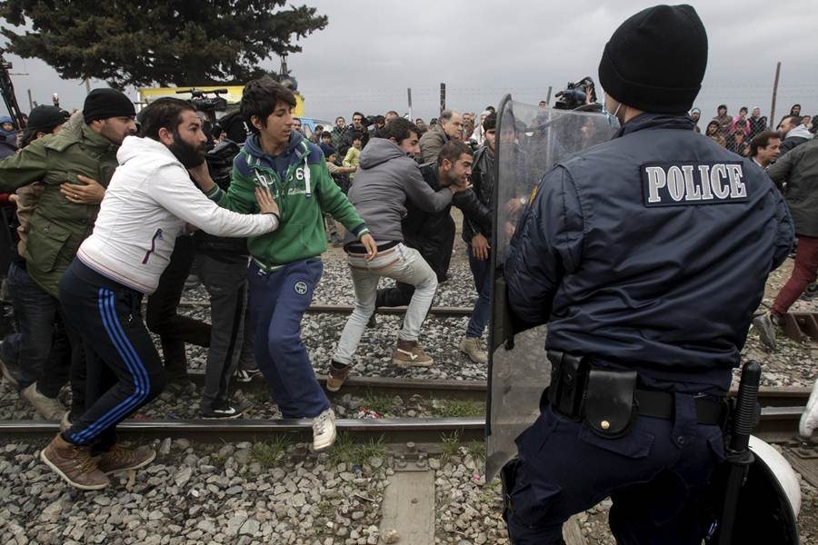 Stranded refugees and migrants try to break a Greek police cordon in order to approach the border fence at the Greek-Macedonian border, near the Greek village of Idomeni